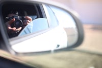 a person is taking a picture with a camera in the rear view mirror of a car